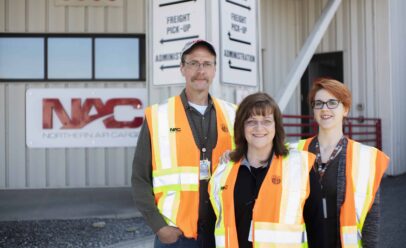 Mark Laura and Sara Smith pose in front of a NAC sign.