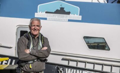 Mike O'Shea smiles and crosses his arms in front of a CITB boat.