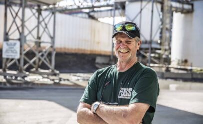 Jack Hagey smiles with arms crossed in a shipyard.