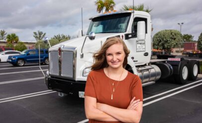 Ashley poses in front of a truck cab.