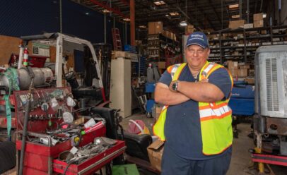 Brita stands in a busy Tropical warehouse, a forklift on his left.