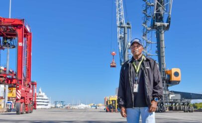 Don poses below shipyard cranes in Tropical hat.