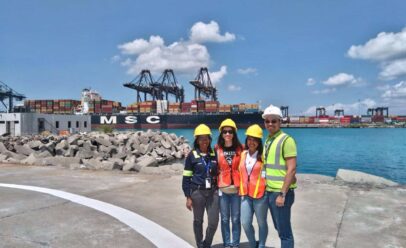 Julissa Moreta poses in a Tropical shipyard with her family. All wear reflective vests and hard hats.