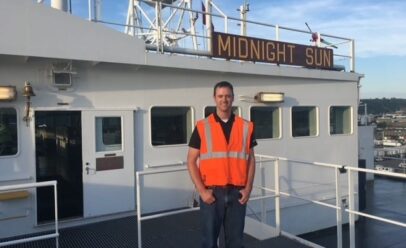 Zack Midles poses for a photo in an orange reflective vest on the Midnight Sun.