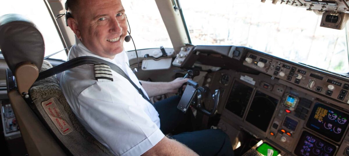 Adam poses with hand on throttle in the cockpit of a NAC jet.